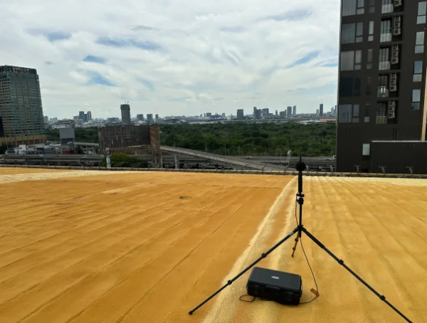 ไมโครโฟนตรวจวัดบนขาตั้งบนดาดฟ้าอาคารระหว่างงานวัดเสียง / Measurement microphone on a tripod on a rooftop during a noise survey